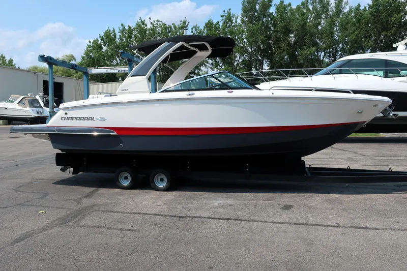 Slide: The Image of 2021 Chaparral 267 SSX boat on trailer, parked outdoors with trees in background. - 3