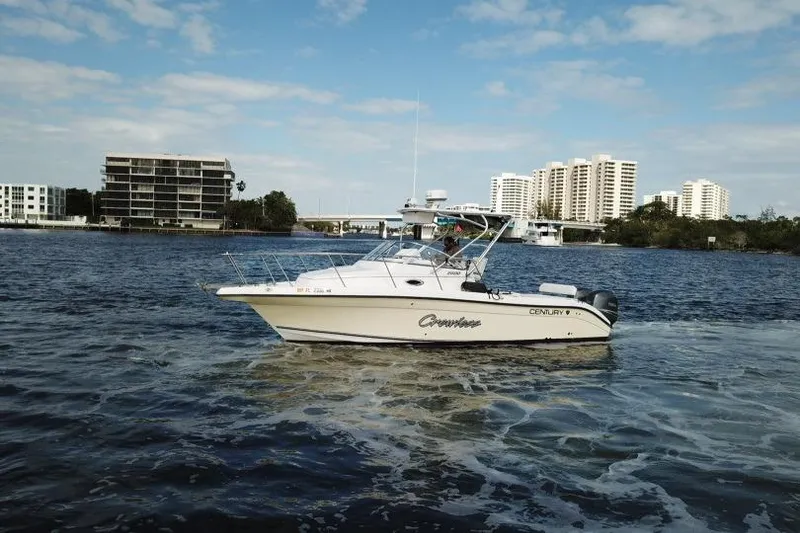 Slide: The Image of 2005 Century 2600 Walk-Around boat cruising on a scenic waterway with city skyline. - 2