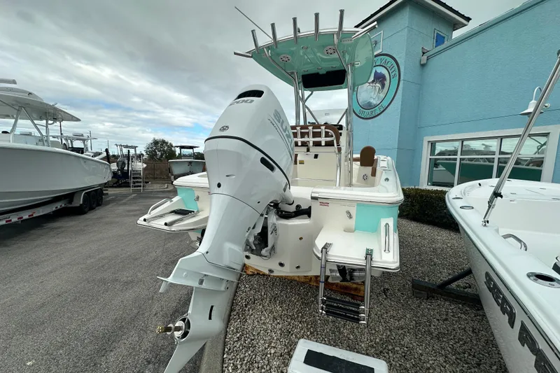 Slide: The Image of 2026 Pioneer 220 Bay Sport boat with powerful outboard motor, parked near a blue building. - 3