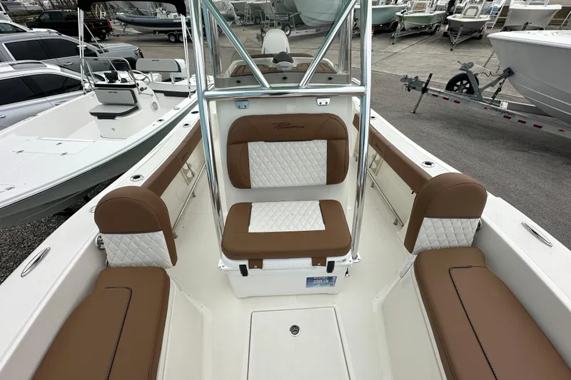 Slide: The Image of 2026 Pioneer 220 Bay Sport boat interior with brown and white seating, docked among other boats. - 7