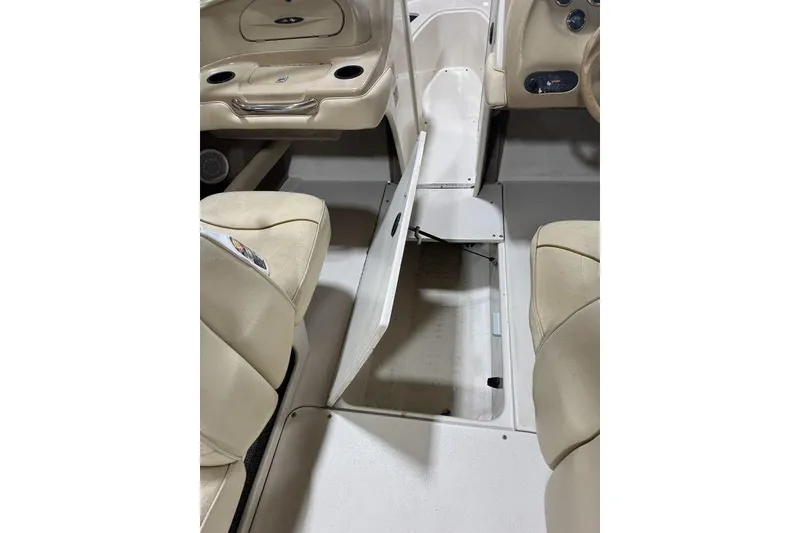 Slide: The Image of 2000 Sea Ray 210 Bow Rider interior with open storage compartment and beige seating. - 6