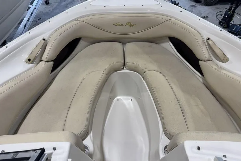 Slide: The Image of 2000 Sea Ray 210 Bow Rider boat interior with beige seating and logo. - 7