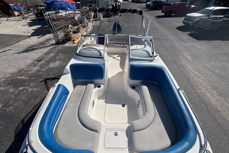 Slide: The Image of 2006 Hurricane SunDeck 217 OB boat with spacious seating and blue accents, parked outdoors. - 21