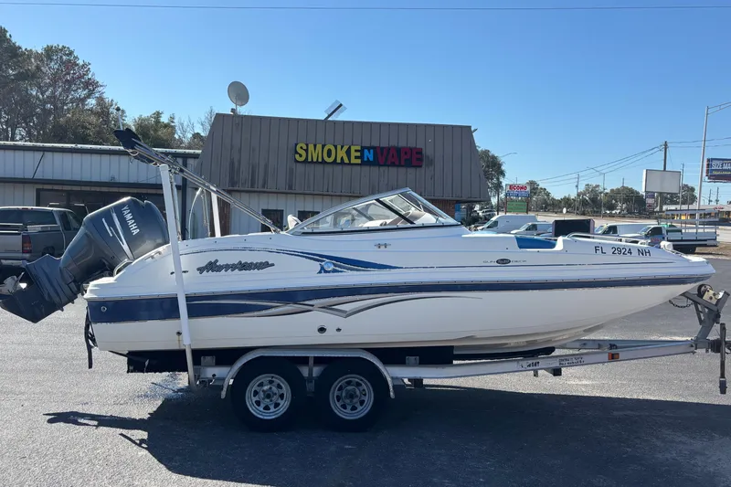 Slide: The Image of 2006 Hurricane SunDeck 217 OB boat on trailer, parked near a store. - 3
