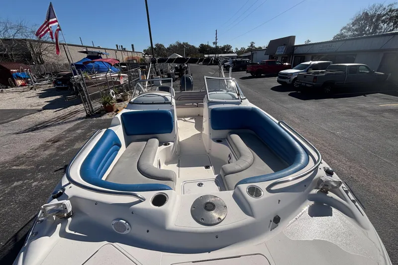 Slide: The Image of 2006 Hurricane SunDeck 217 OB boat with blue and gray seating, parked outdoors. - 8