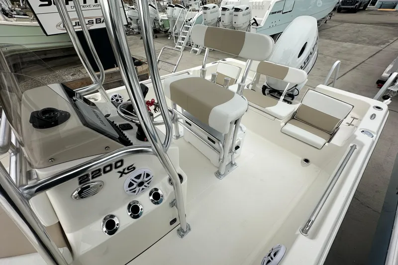Slide: The Image of 2026 Bulls Bay 2200 XS boat interior with seating and control panel in a marina. - 12