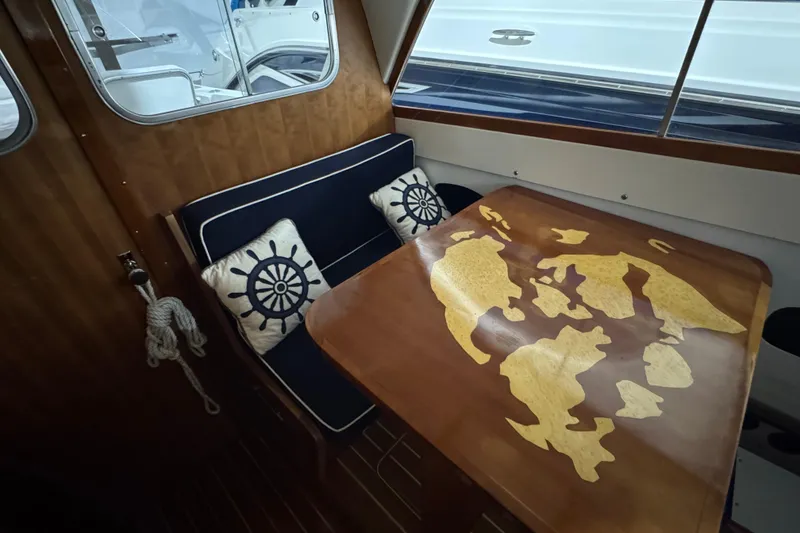 Slide: The Image of 1974 Bertram 31 Flybridge Cruiser interior with nautical-themed cushions and a wooden table. - 20