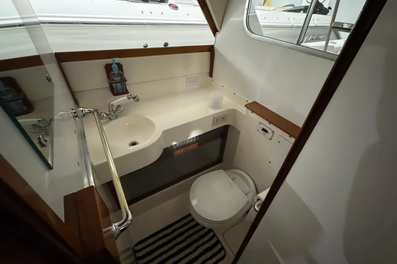 Slide: The Image of 1974 Bertram 31 Flybridge Cruiser bathroom with sink, toilet, and striped rug. - 22