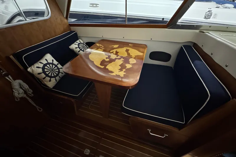 Slide: The Image of 1974 Bertram 31 Flybridge Cruiser interior with nautical-themed cushions and wooden table. - 25