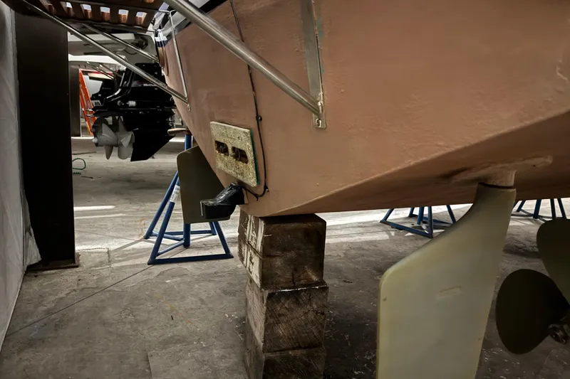 Slide: The Image of 1974 Bertram 31 Flybridge Cruiser on blocks, showing propellers and rudders in a workshop. - 33