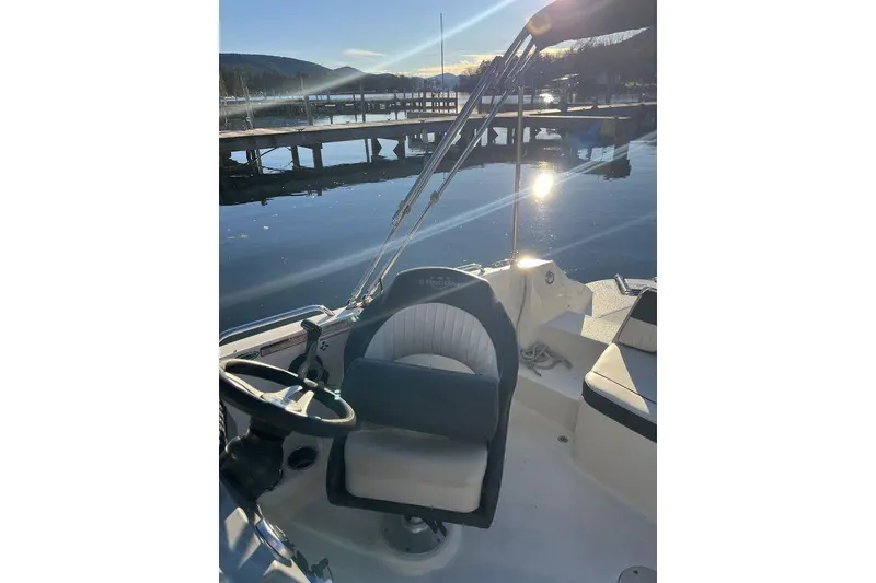 Slide: The Image of 2016 Stingray 192 SC boat interior with steering wheel, dock, and scenic water view. - 11