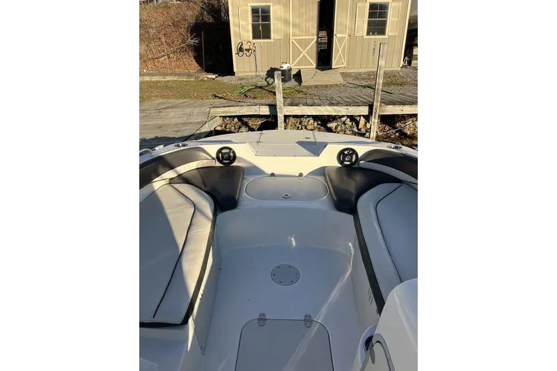 Slide: The Image of 2016 Stingray 192 SC boat interior with seating and storage, docked near a wooden shed. - 5