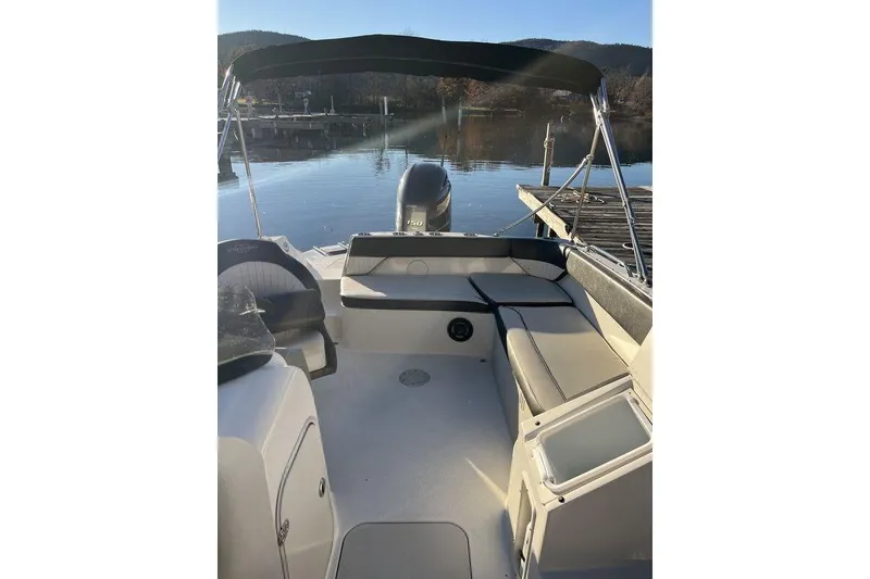 Slide: The Image of 2016 Stingray 192 SC boat interior with seating and canopy on calm water. - 7