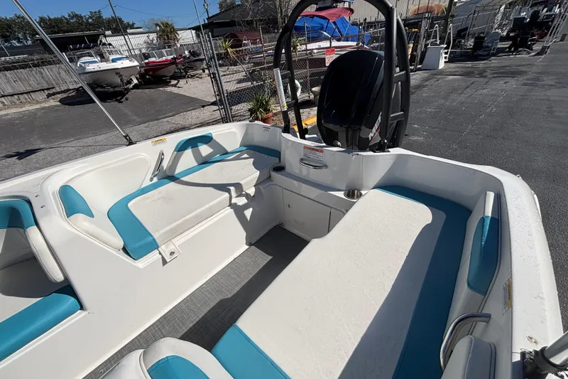 Slide: The Image of 2021 Bayliner Element E18 boat interior with blue and white seating, docked outdoors. - 11