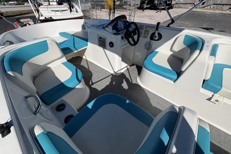 Slide: The Image of 2021 Bayliner Element E18 boat interior with blue and white seating, steering console, and cup holders. - 12