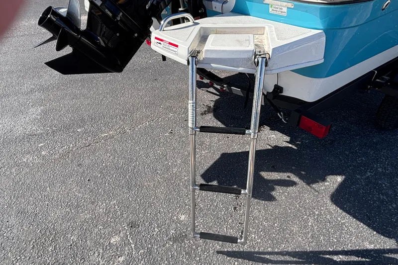 Slide: The Image of 2021 Bayliner Element E18 boat with extended swim ladder on asphalt surface. - 19