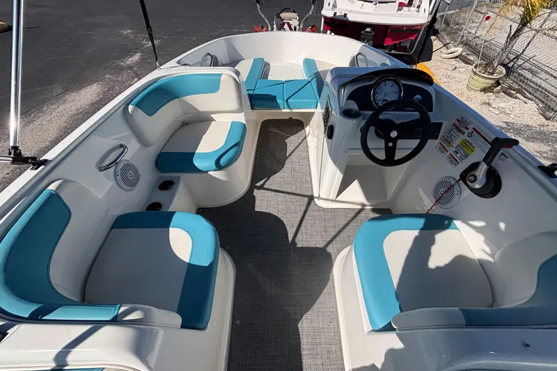 Slide: The Image of 2021 Bayliner Element E18 boat interior with blue and white seating, steering wheel, and dashboard. - 26