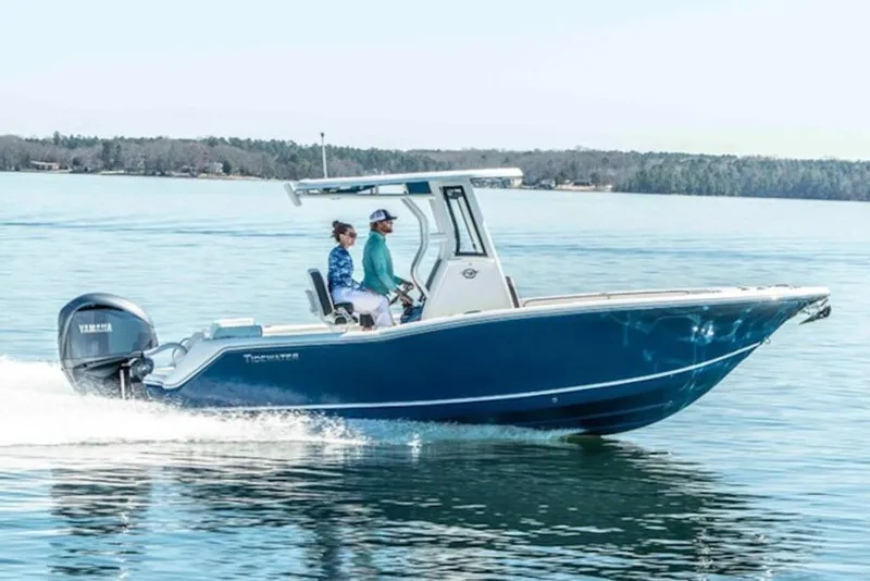 The Image of 2026 Tidewater 232 LXF boat cruising on a calm lake with two passengers. - 1