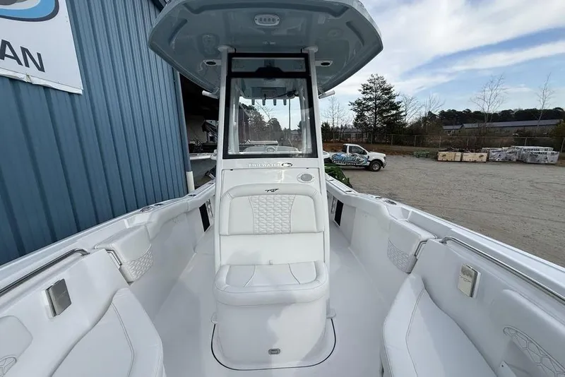 Slide: The Image of 2026 Tidewater 232 LXF boat interior with white seating and console, docked outdoors. - 16
