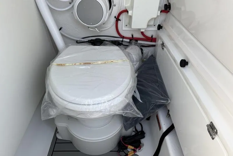 Slide: The Image of 2026 Tidewater 232 LXF boat interior with a compact marine toilet setup. - 37