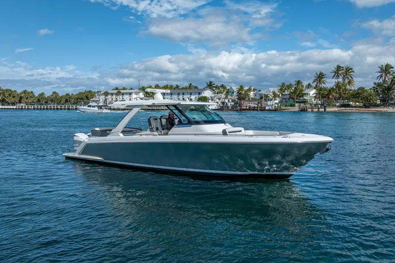 The Image of 2019 Tiara Sport 38 LS boat cruising on clear blue water near a tropical shoreline. - 0