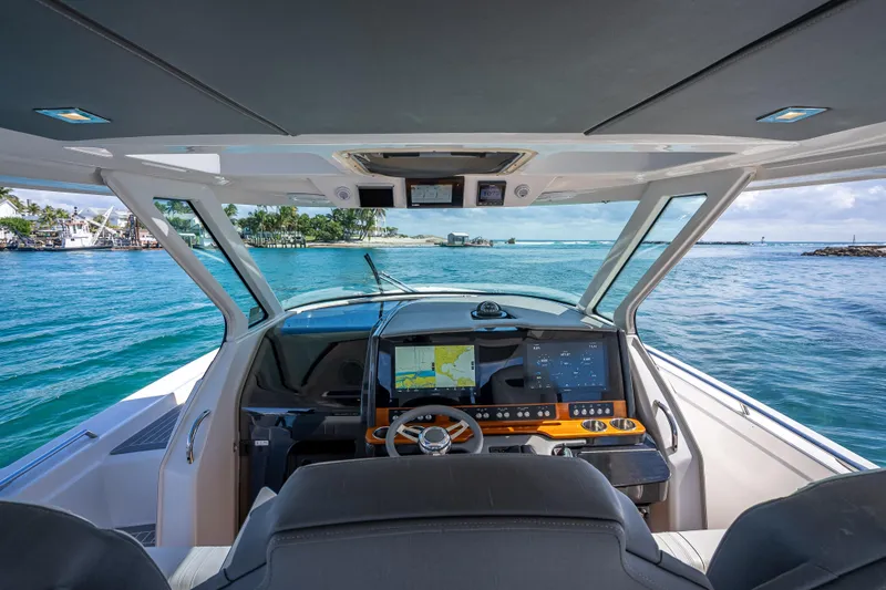 Slide: The Image of 2019 Tiara Sport 38 LS boat cockpit with navigation screens, steering wheel, and ocean view. - 22