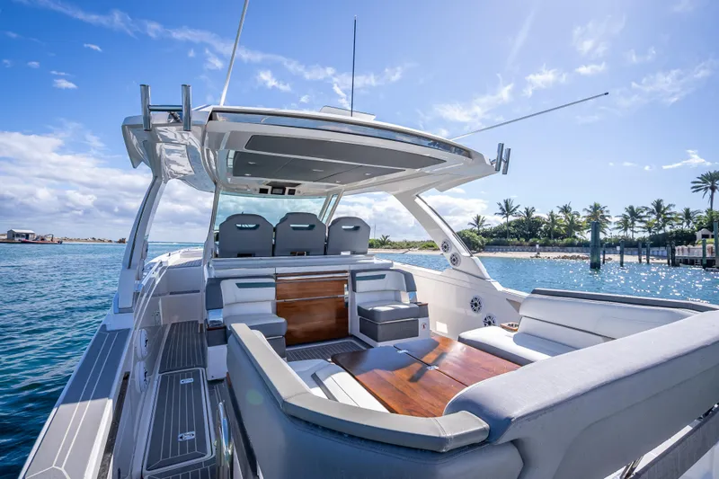 Slide: The Image of 2019 Tiara Sport 38 LS luxury yacht with spacious seating, docked by palm trees under a clear sky. - 9