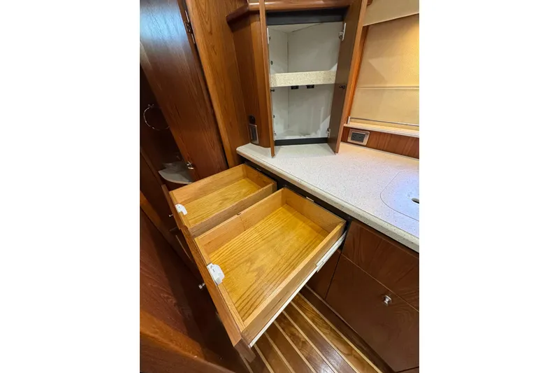 Slide: The Image of 2007 Tiara 43 yacht interior with open wooden drawers and cabinets in the kitchen area. - 22