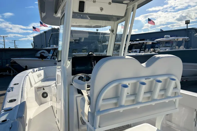 Slide: The Image of 2026 Sea Fox 268 Commander boat interior with helm and rod holders, docked under blue sky. - 22