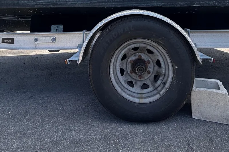 Slide: The Image of Trailer wheel of a 2020 Clearwater 2000 Center Console boat on pavement. - 104