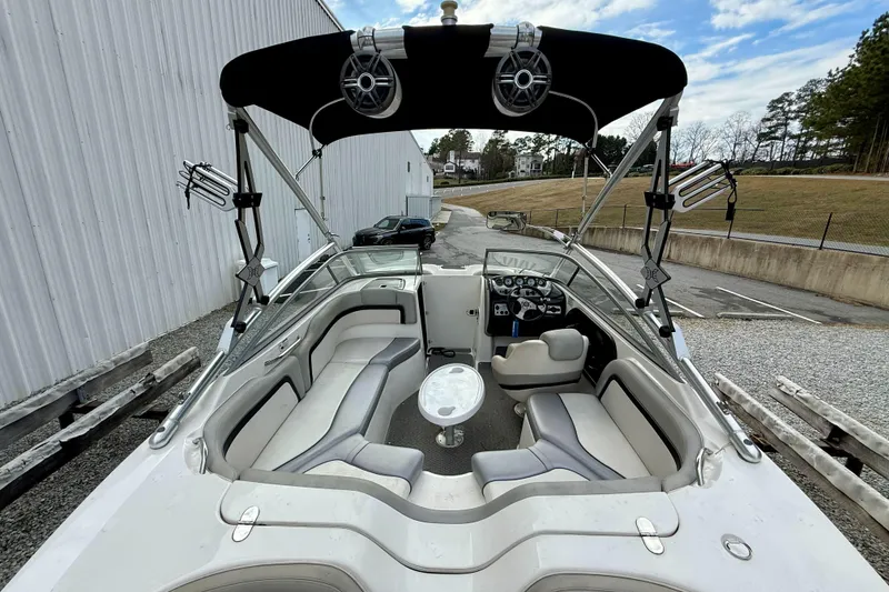 Slide: The Image of 2010 Yamaha Boats 212X interior with seating, steering, and speakers, docked outdoors. - 11