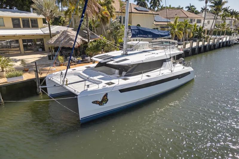Slide: The Image of 2021 Leopard 50 catamaran docked by waterfront homes, featuring a butterfly decal. - 117