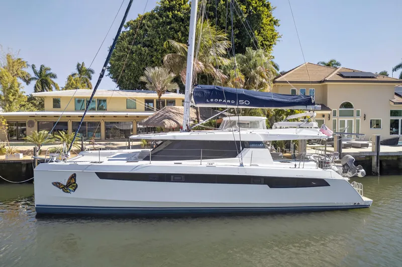 Slide: The Image of 2021 Leopard 50 catamaran docked by waterfront homes, featuring a butterfly decal. - 118
