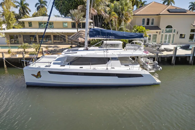 Slide: The Image of 2021 Leopard 50 catamaran docked by waterfront homes, featuring a butterfly decal. - 119
