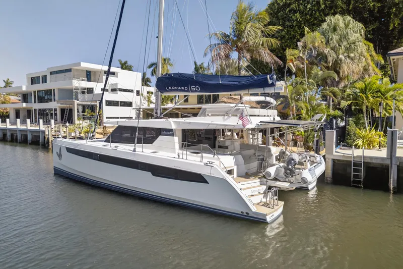 Slide: The Image of 2021 Leopard 50 catamaran docked by modern waterfront home, surrounded by palm trees. - 120