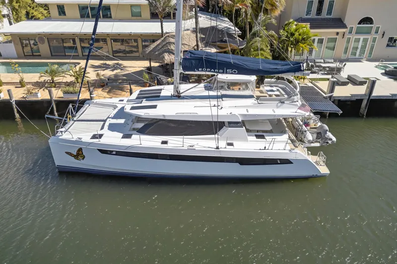 Slide: The Image of 2021 Leopard 50 catamaran docked by waterfront home, featuring sleek design and butterfly decal. - 125