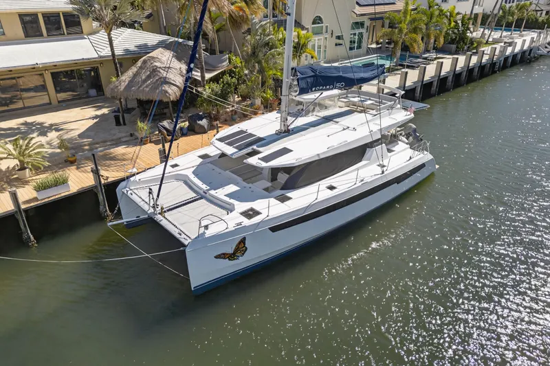 Slide: The Image of 2021 Leopard 50 catamaran docked by waterfront homes, featuring sleek design and butterfly decal. - 127