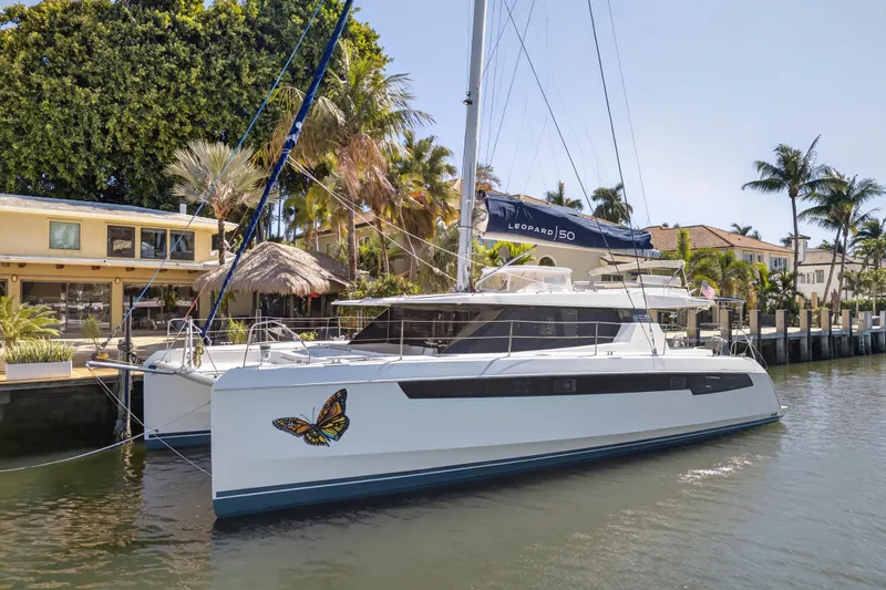 The Image of 2022 Leopard 50 catamaran docked by waterfront homes, surrounded by lush greenery. - 0