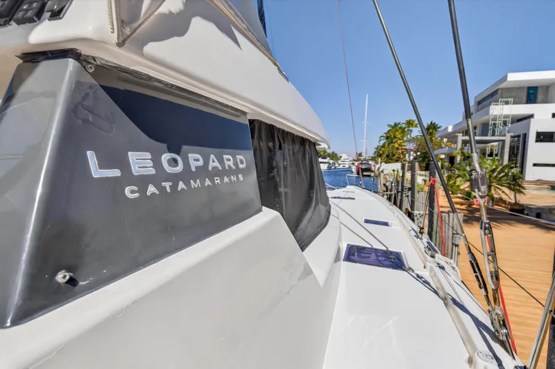 Slide: The Image of 2022 Leopard 50 catamaran deck with seating and netting, docked near lush greenery. - 39