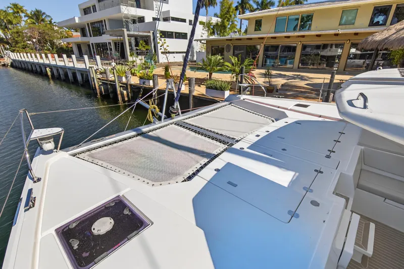 Slide: The Image of 2022 Leopard 50 catamaran docked by waterfront homes, featuring spacious deck and lush surroundings. - 40