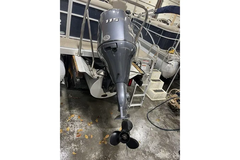 Slide: The Image of 2018 Bennington 23 SLX boat with 115 horsepower outboard motor in a garage setting. - 15