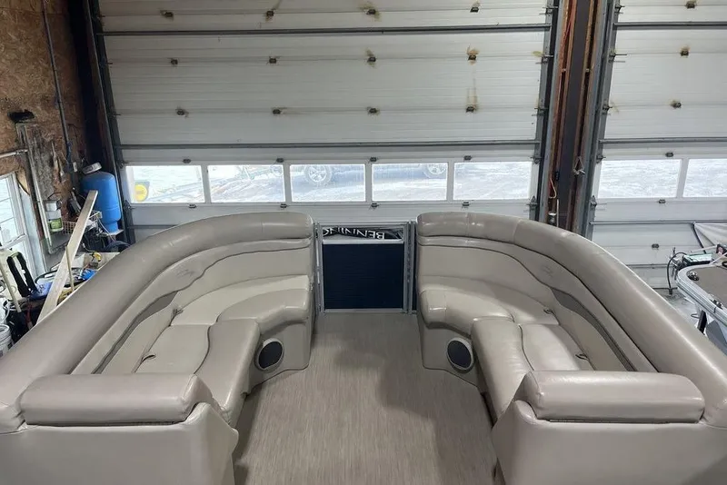Slide: The Image of 2018 Bennington 23 SLX pontoon boat interior with beige seating in a garage. - 4