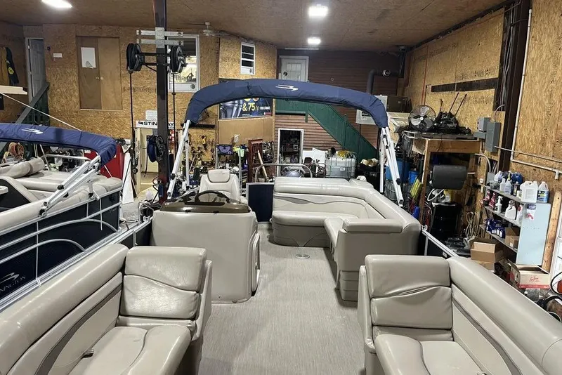Slide: The Image of 2018 Bennington 23 SLX pontoon boat in a garage, featuring spacious seating and a blue canopy. - 7