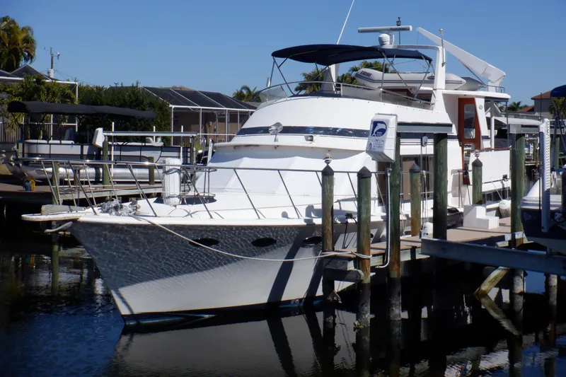 The Image of 1990 Marine Trader 47 Tradewinds yacht docked at a marina under clear blue skies. - 0
