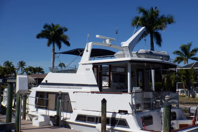 Slide: The Image of 1990 Marine Trader 47 Tradewinds yacht docked, surrounded by palm trees under a clear blue sky. - 2