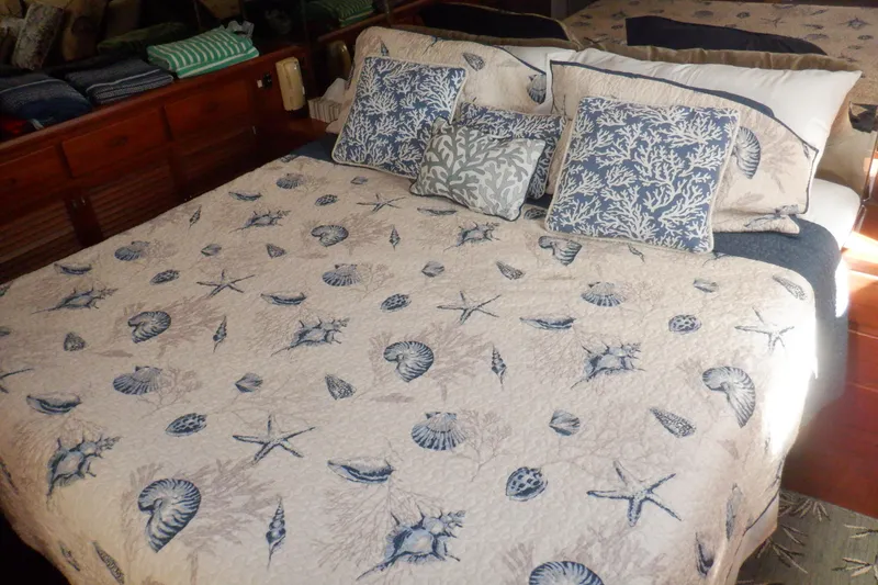 Slide: The Image of Cozy bedroom on 1990 Marine Trader 47 Tradewinds with nautical-themed bedding and pillows. - 42