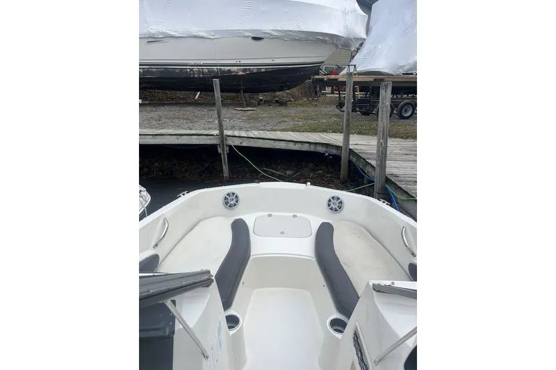 The Image of 2017 Stingray 191 DC boat interior with seating, docked near covered boats. - 1