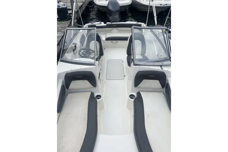 Slide: The Image of 2017 Stingray 191 DC boat interior with seating and steering wheel at dock. - 2