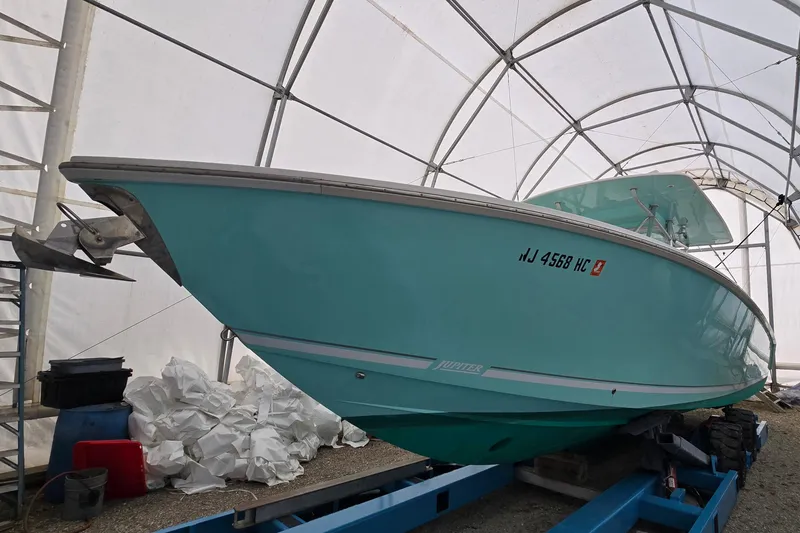 Slide: The Image of 2010 Jupiter 34 FS boat in storage, turquoise hull, covered shelter. - 3