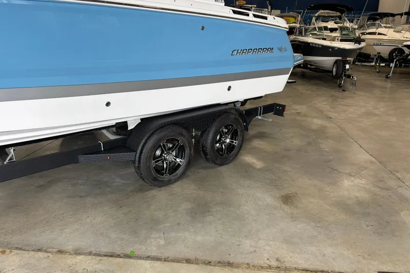 Slide: The Image of 2026 Chaparral SSX 4 boat on trailer in showroom, featuring sleek blue and white design. - 4